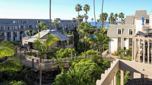 A resort with multiple-story buildings, palm trees, and a view of the ocean.