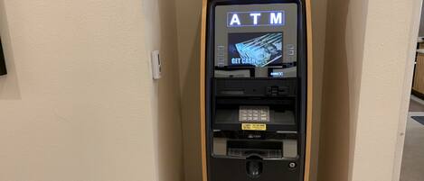 An ATM machine with a wooden cabinet, a card reader, and a cash dispenser.