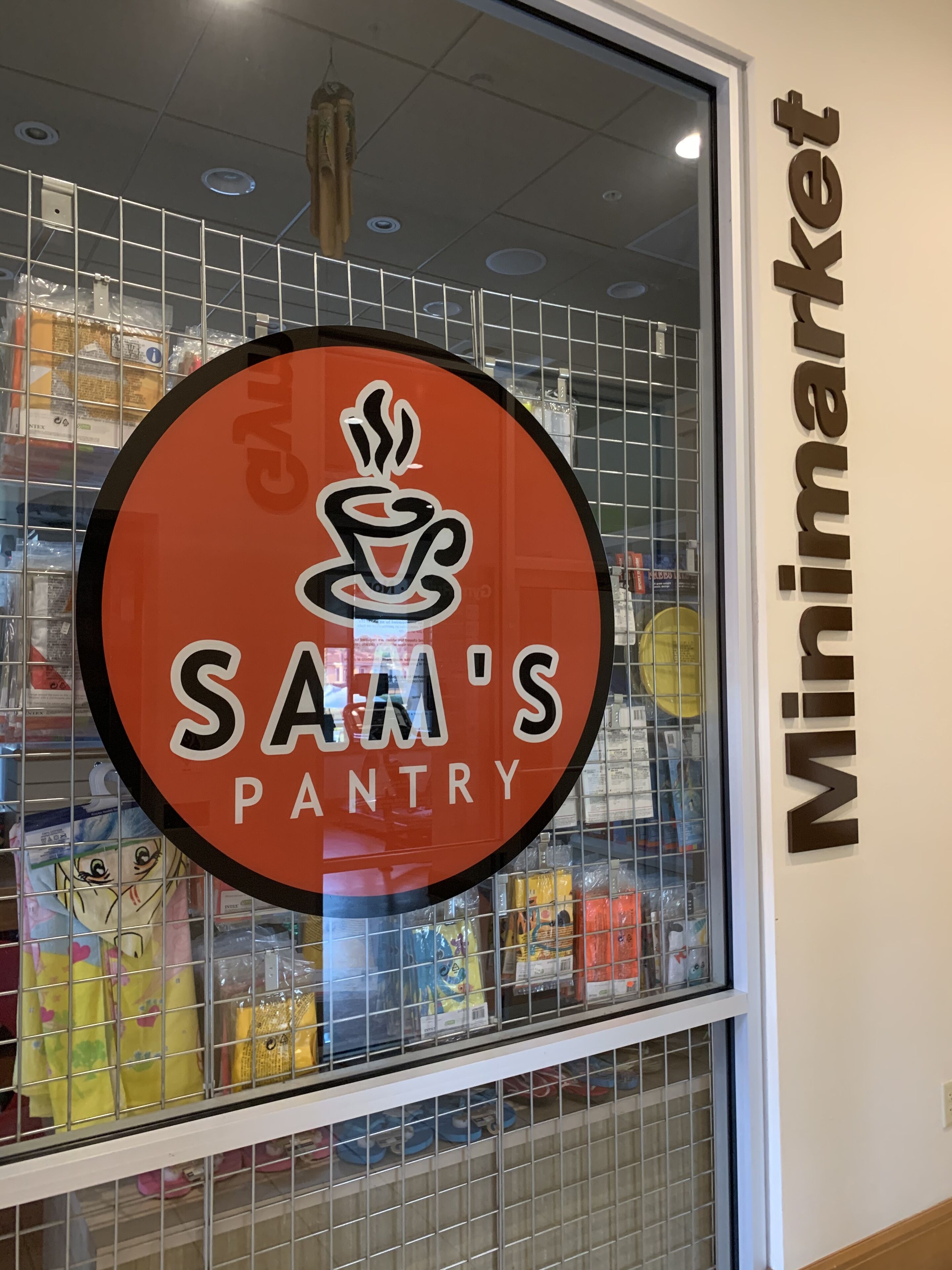 A storefront with a sign reading "SAM'S PANTRY" and a glass display case filled with various items.