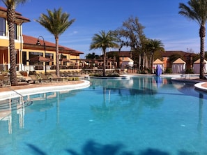 A resort pool area with lounge chairs and palm trees.