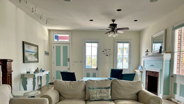 Uma sala de estar com um sofá em seção bege, uma mesa de centro de vidro e uma lareira.