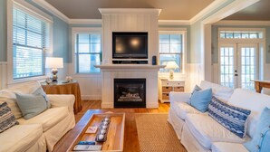 Una sala de estar con chimenea, televisor y dos sofás.