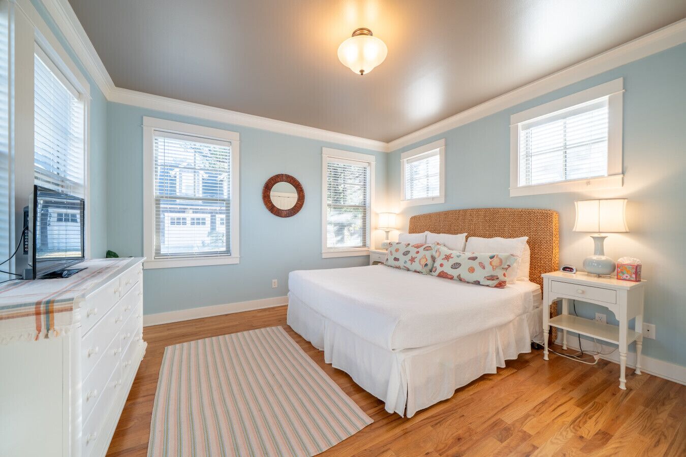 A bedroom with a bed, dresser, nightstand, lamp, and a wall clock.