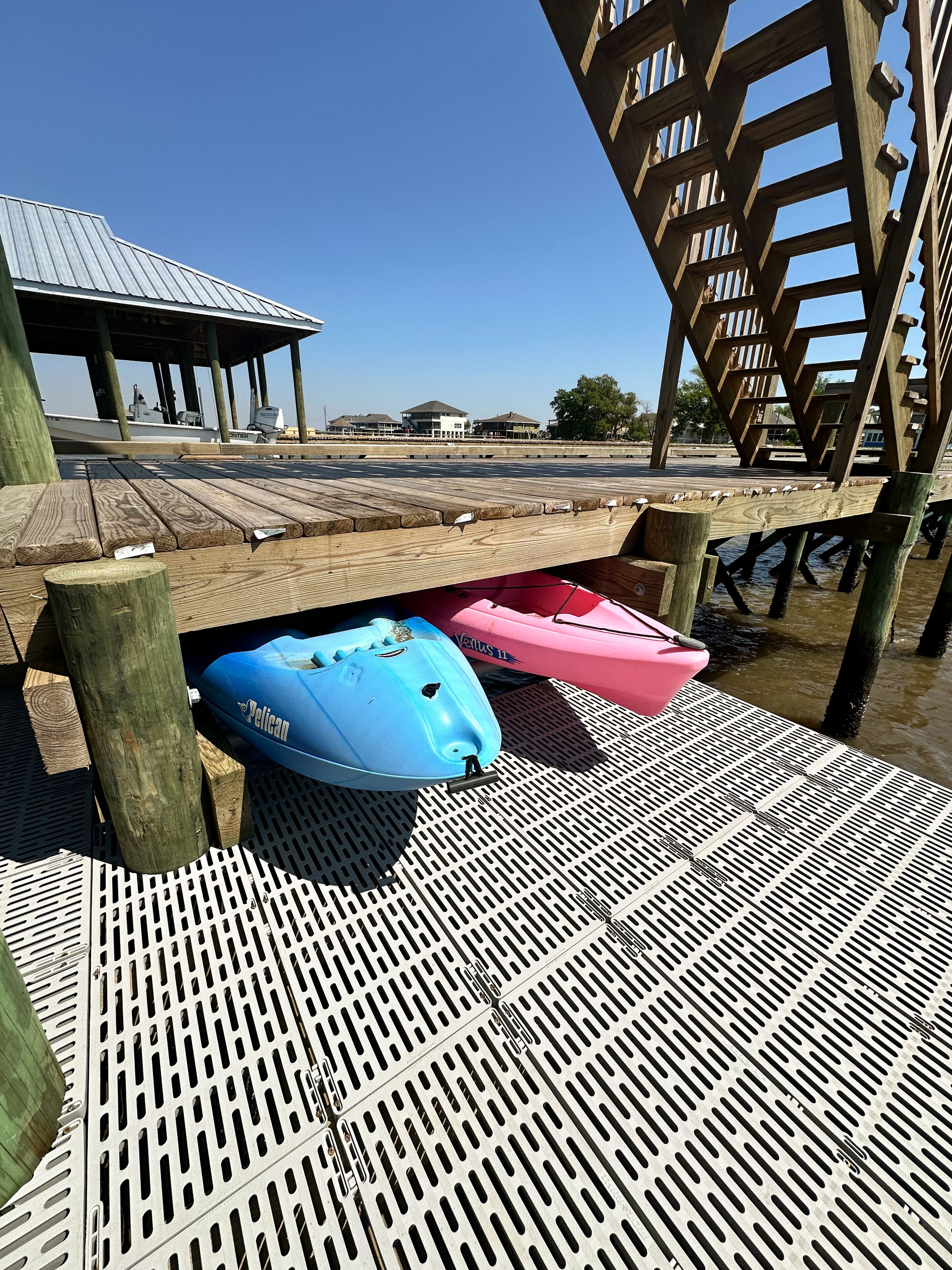 A wooden pier with a metal grate floor, two inflatable boats, and a wooden structure in the background.