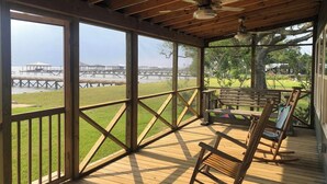 Una terraza de madera con vista a un muelle y una zona ajardinada.