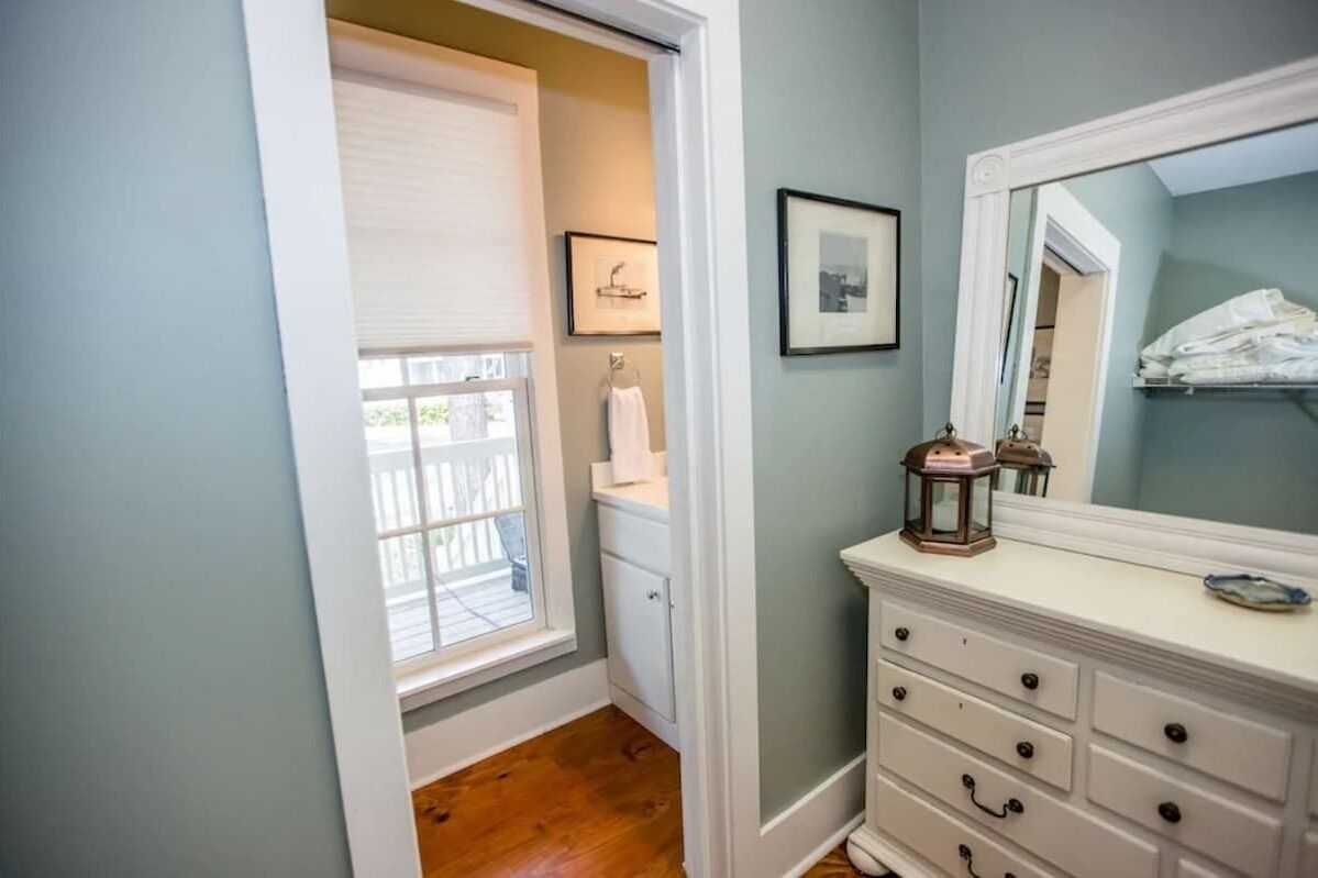A bathroom with a white vanity, a mirror, and a window with blinds.