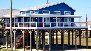 Une maison à deux étages dotée d’un balcon, d’une terrasse en bois et d’un escalier menant à l’étage supérieur.