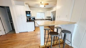 Una cocina con una isla central, armarios blancos y suelo de madera.