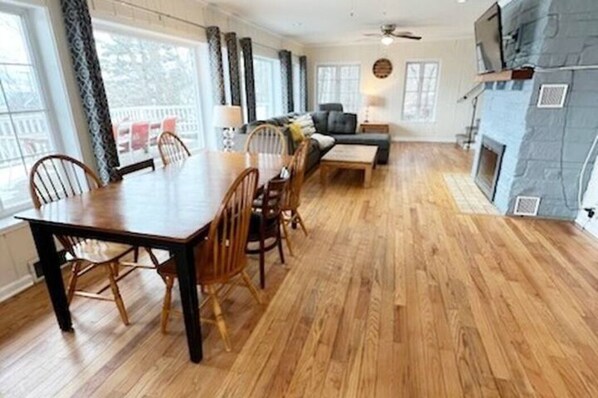Ein geräumiges Wohnzimmer mit Esstisch aus Holz, gemütlicher Sitzgelegenheit und Kamin.