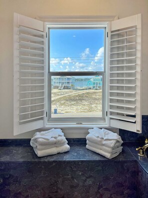 A bathroom with a window, white towel stacks, and a marble countertop.