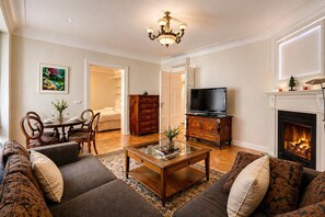 Un salon comprenant un ensemble de canapés, une table basse, un téléviseur, une cheminée et un coin repas avec des chaises et une table.