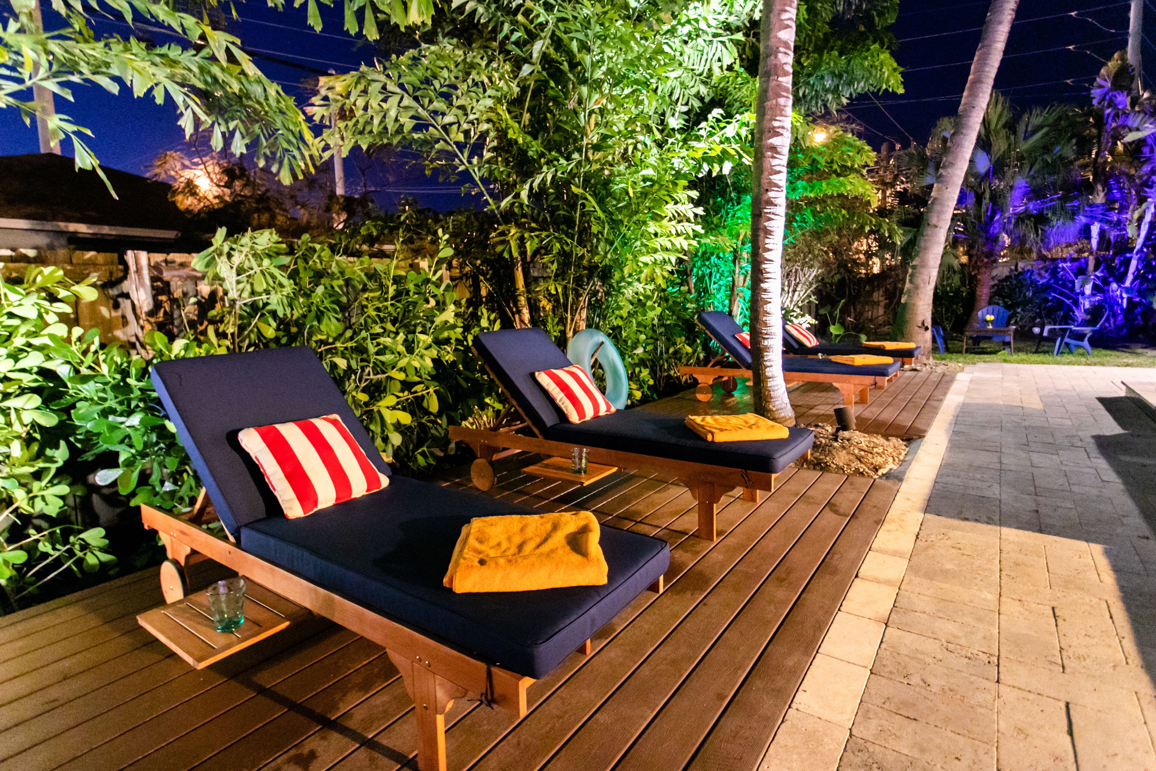 Dos sillones de exterior con cojines, una terraza de madera y follaje circundante.