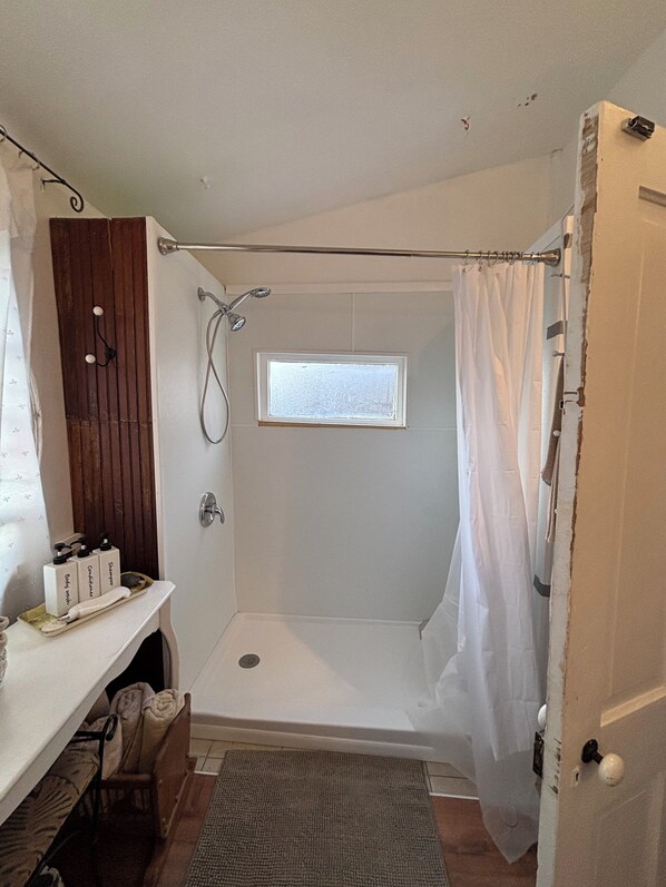 A small, compact bathroom with a shower, a window, and a towel rack.
