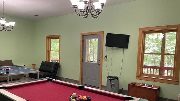 A pool table with balls, a television mounted on the wall, and a door with windows.