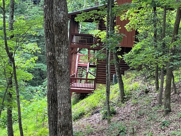 Una cabaña de madera con balcón, rodeada por un bosque frondoso.