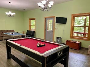 A pool table with balls, a sofa, a chair, a television, and windows with a view. - Alpenhaus Cabins-Pet Friendly Helen Cabin Hot Tub (Helen)