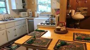 A kitchen with white cabinets, a stove, and a sink. There are placemats with a green design on the table. - Stone Cottage is located in a beautiful mountain gorge (Gerton)