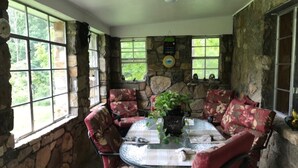 A stone-walled room with a round glass table and floral-patterned chairs. - Stone Cottage is located in a beautiful mountain gorge (Gerton)