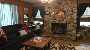 A cozy living room with a stone fireplace, a dark-colored sofa, and a coffee table. - Stone Cottage is located in a beautiful mountain gorge (Gerton)