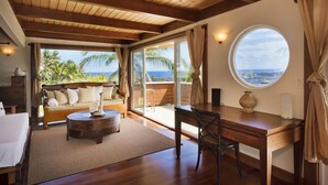 A room with a wooden ceiling, a round table, a sofa, and a view of the ocean through large windows. - Luxuriously Appointed Bali Temple Has 160 Degree Ocean Views! (Pahoa)