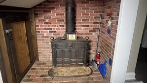A corner room with a brick fireplace, a wooden door, and a wooden floor. - Newly Renovated Country Home Located near Greenbrier River (Alderson)