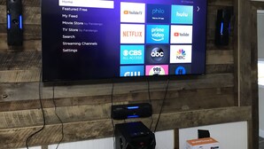 A flat-screen TV mounted on a wooden wall displaying a streaming service interface with various channel logos. - Newly Renovated Country Home Located near Greenbrier River (Alderson)