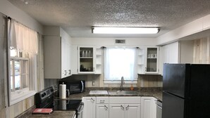 A kitchen with white cabinets, a black refrigerator, a microwave, and a sink. - Newly Renovated Country Home Located near Greenbrier River (Alderson)