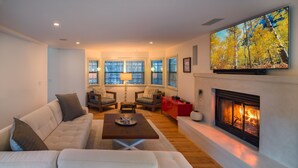 Una sala de estar con chimenea, un sofá, una mesa de centro y un televisor montado en la pared.