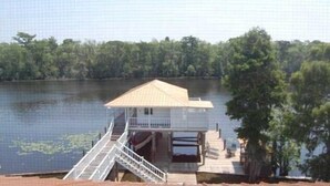A houseboat with a small deck and a staircase leading to the entrance. - Louisiana Tickfaw River House Near New Orleans, Baton Rouge! Best Views! HotTub! (Springfield)