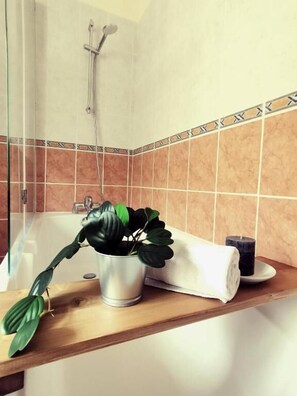 A bathroom with a bathtub, a shower, and a potted plant on the counter. - Auberge de Chanteuges (Chanteuges)
