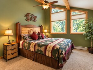 A bedroom with a bed, two bedside lamps, a ceiling fan, a window, and a potted plant. - Luxury lodging minutes from Glacier National Park. (East Glacier Park)
