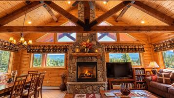 A cozy cabin interior with a stone fireplace, wooden furniture, and a television.