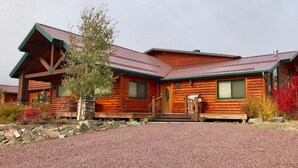 A log cabin with a metal roof, a front porch, and a stone foundation.