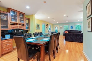 A dining area with a wooden table, chairs, and a kitchen with cabinets and a countertop. - Sunbeam-Soundview Private Home. 2 Min Walk to the Beach (Navarre)