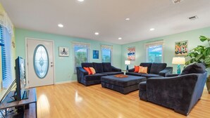 A living room with two dark sofas, a coffee table, and a TV on a wooden stand. - Sunbeam-Soundview Private Home. 2 Min Walk to the Beach (Navarre)