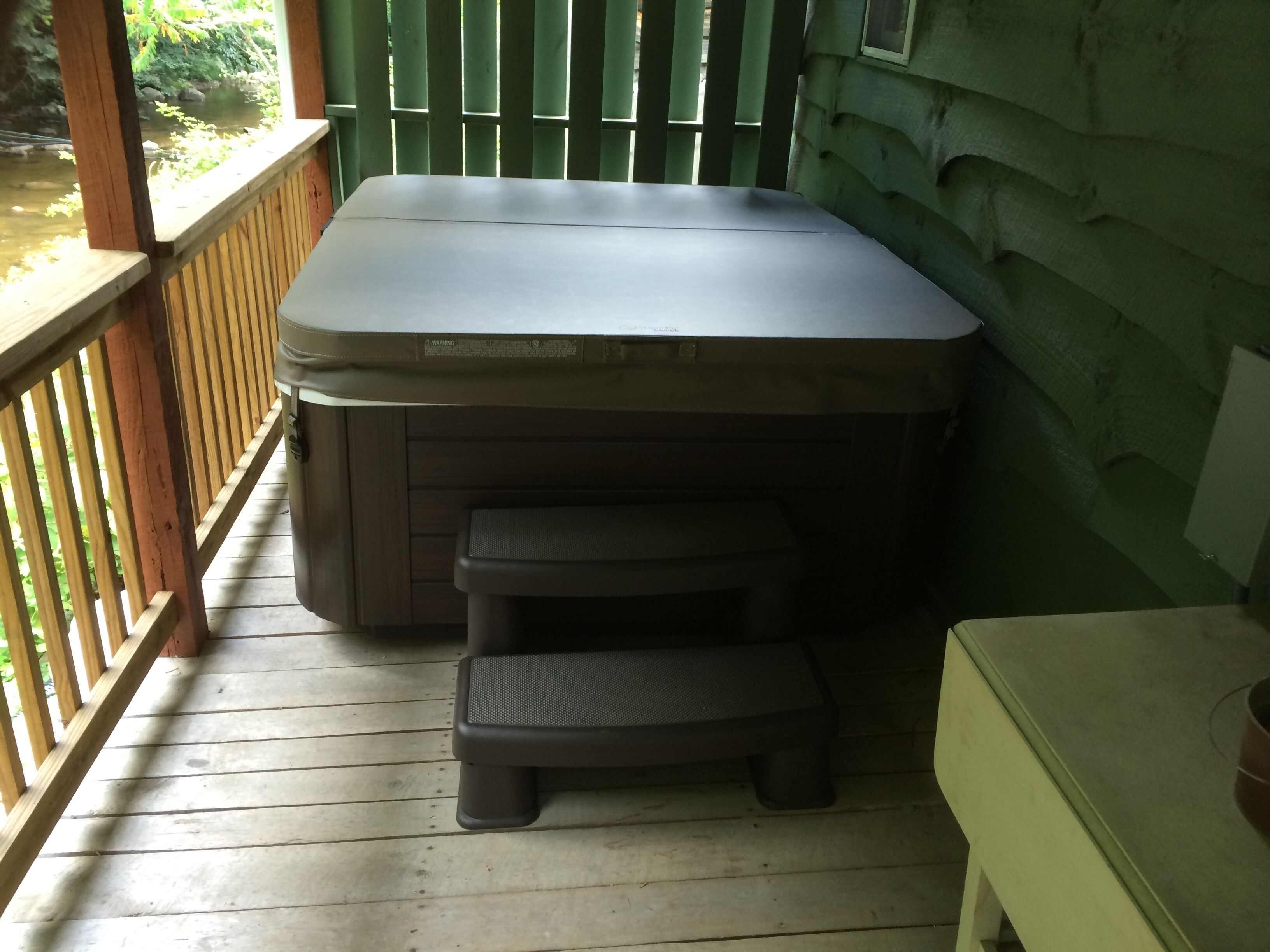 Ein Whirlpool mit Stufen auf einer Holzterrasse.