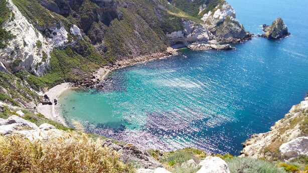 Een kustlandschap met rotsachtige kliffen en een heldere blauwe zee.