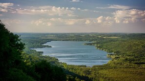 A river winding through a densely forested landscape with a clear sky above. - Spring Summer specials on newly remodeled lakefront home. May also book 2664590 (CANADICE)