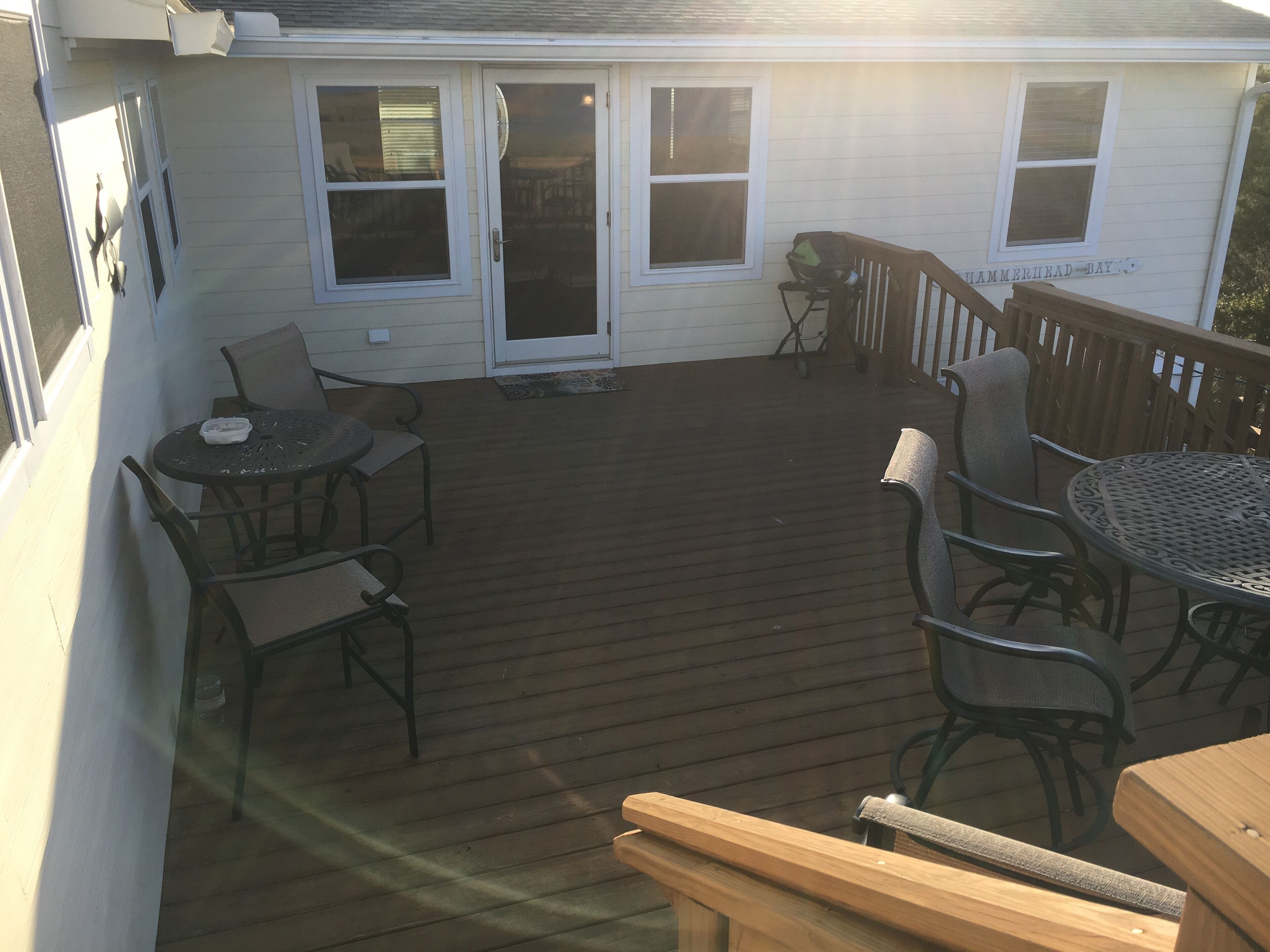 A covered patio with a wooden deck, outdoor seating, and a view of the ocean.