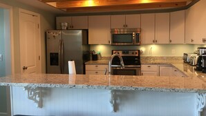 A kitchen with a granite countertop, stainless steel appliances, and wooden ceiling beams. - Kayaker and Bird Watchers Dream: Freshly Renovated with Breathtaking Views (Cedar Point)