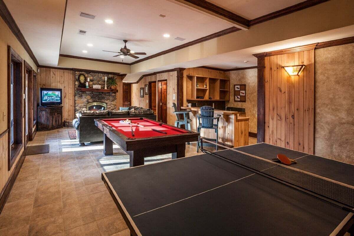 Una habitación amplia con mesa de billar, mesa de ping pong y chimenea.
