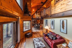 Ein gemütliches Blockhaus-Interieur mit Holzwänden, einer Ledersofa, einem Essbereich und einem Kamin.