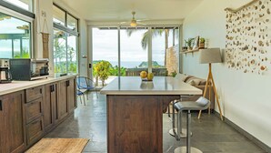 Een moderne keuken met een groot kookeiland, een eetgedeelte met uitzicht en een woonruimte met uitzicht op het strand.