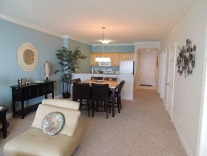 Cozy living space with a kitchenette, sofa, dining table, and potted plant.