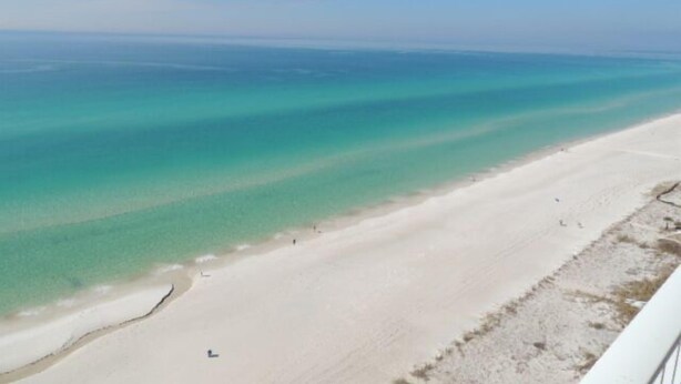 Une plage à l’eau turquoise et limpide, bordée d’un rivage sablonneux.