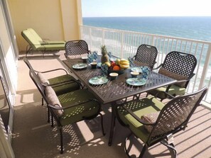Enjoy al fresco dining on the balcony with ocean views, featuring a table set with a selection of fresh fruits and dishes.