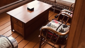 A cozy cabin interior with a wooden table, wicker sofa, and chairs. - Lake Front Cabin on Squam Lake/On Golden Pond (Center Harbor)