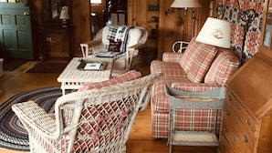 A cozy room with a wicker chair, a plaid sofa, and a wooden dresser. - Lake Front Cabin on Squam Lake/On Golden Pond (Center Harbor)