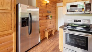 Eine Küche mit Holzwänden, einem Edelstahlkühlschrank, einer Mikrowelle und einem Backofen.