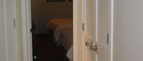 A hotel room with a closed door, a bed, and a bedside table.